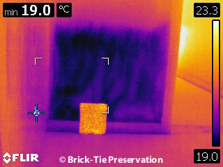 Thermal image of a wall saturated at the base due to a leak – note the diffuse reflector used for quantitative measurement of temperatures