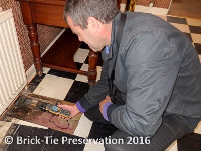 A surveyor using an electronic moisture meter to check the floor timbers are safe from decay