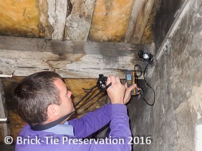 Here our surveyor is using deep hammer electrodes to check the moisture content of the end of a roof purlin on a westerly facing wall. He also photographs the high readings for his client.